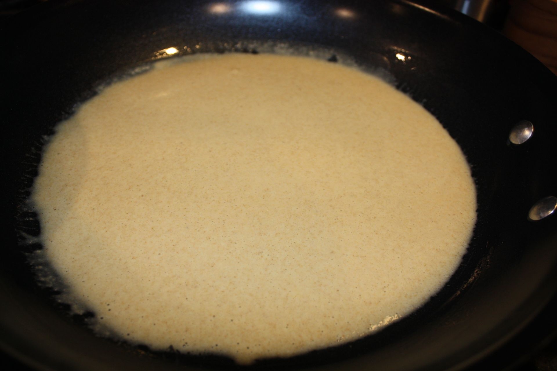 the crepe batter is spread all over the pan